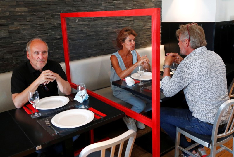 People test a protective plexiglass barrier in a restaurant in