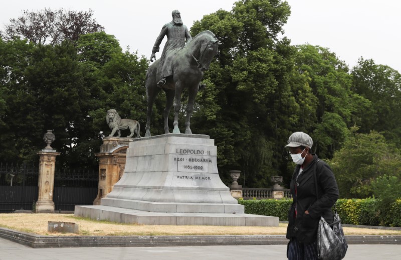 Person walks past the statue of Belgian King Leopold II,