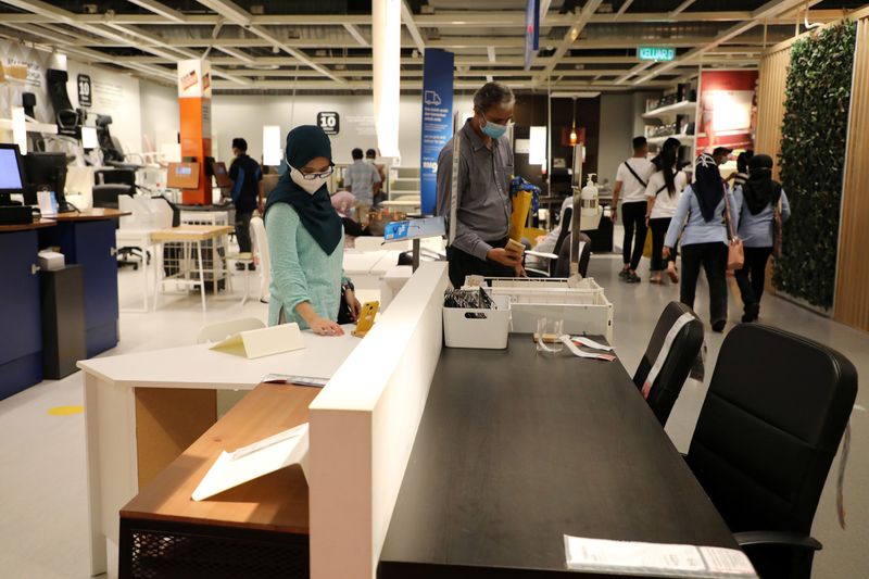 Customers wearing protective masks shop for office furniture at IKEA,