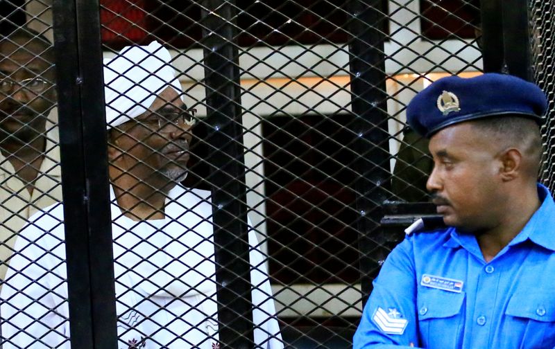 Sudan’s former president Omar Hassan al-Bashir sits inside a cage