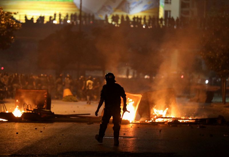 A member of the Lebanese riot police walks near burning