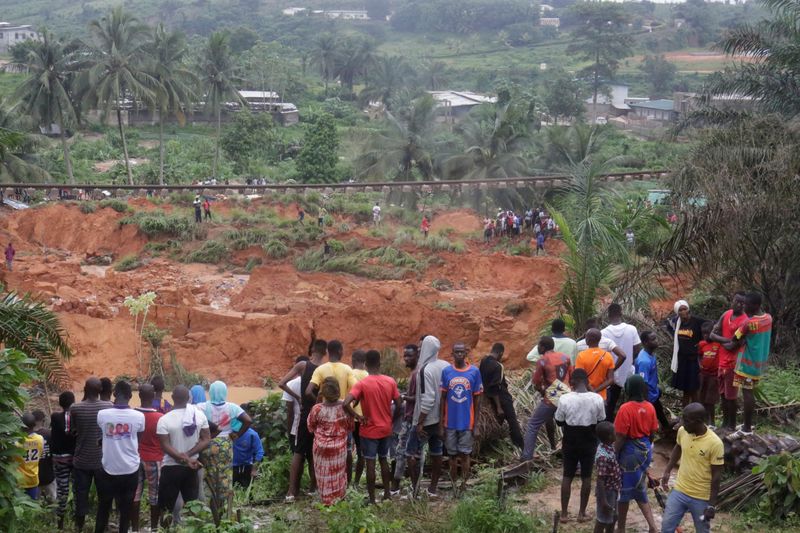 People watch an area affected by landslide after unusually heavy