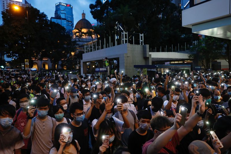 Pro-democracy demonstrators march holding their phones with flashlights on during