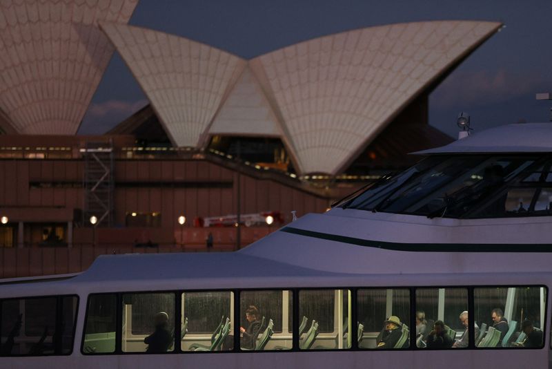 Passengers ride a ferry past the Sydney Opera House in