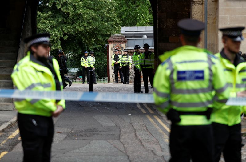 Police officers stand behind the cordon at the scene of