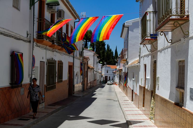 A woman walks past rainbow flags placed on a street