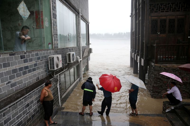 People observe the rising water level of a river at