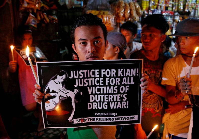 FILE PHOTO: Protesters and residents hold lighted candles and placards