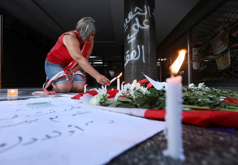 A woman lights a candle at the site where a