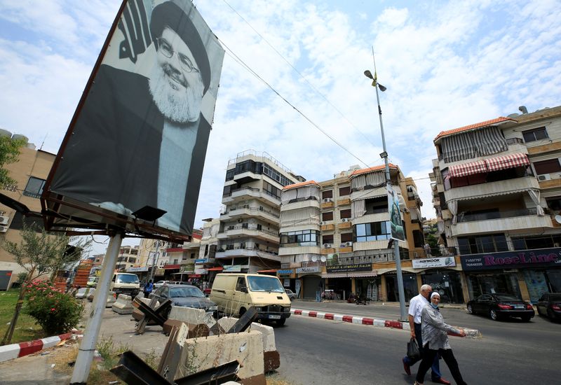 People walk past a poster depicting Lebanon’s Hezbollah leader Sayyed