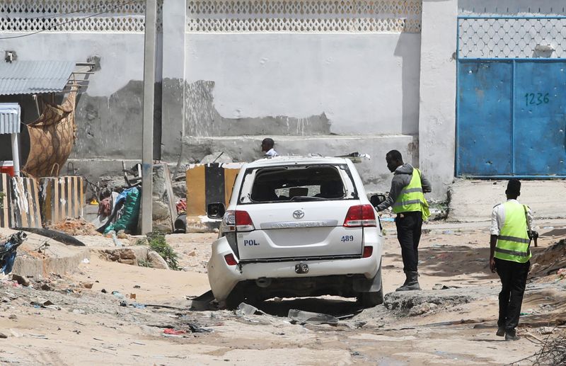 Somali Police officers stands at the scene after roadside bomb