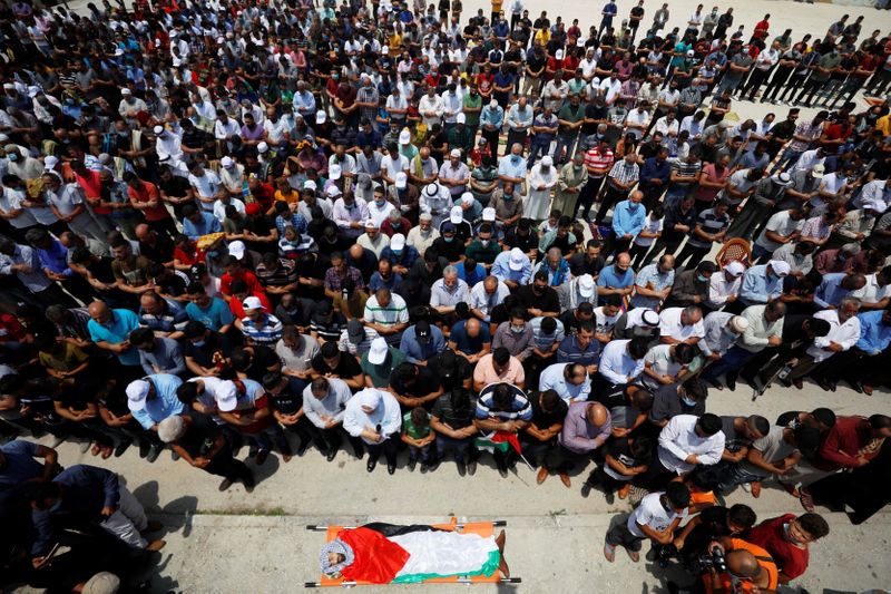 Mourners pray before the body of Palestinian man Yakoub in