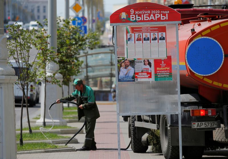 FILE PHOTO: Municipal worker waters the grass near a poster