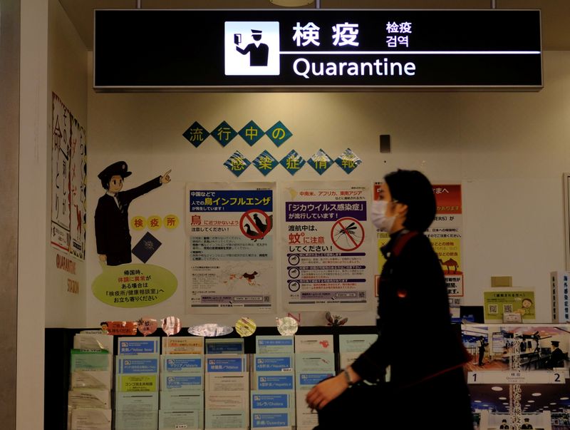 Airline employees wearing masks pass the quarantine counter at Narita