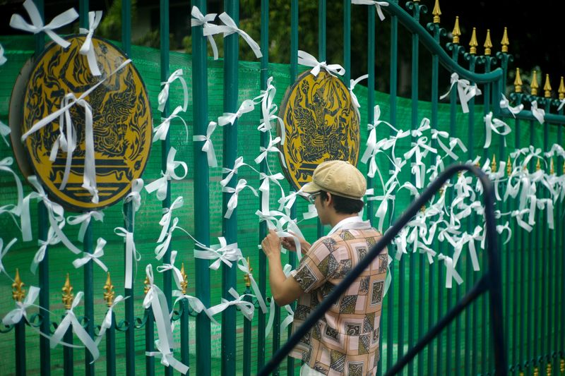 A pro-democracy protester ties white ribbons at the gate of