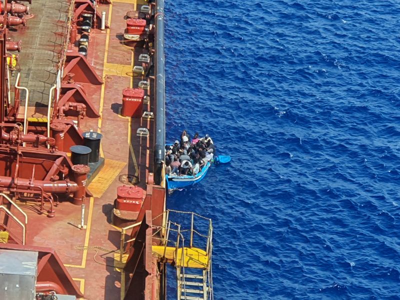 FILE PHOTO: Migrants sit in a boat alongside the Maersk