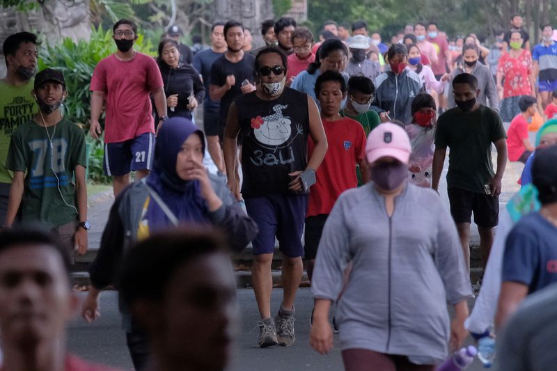 People wearing protective masks walk at the Puputan Margarana Renon