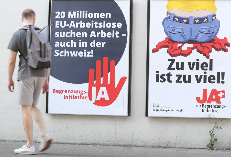 FILE PHOTO:Man walks past posters against the anti-immigration initiative in