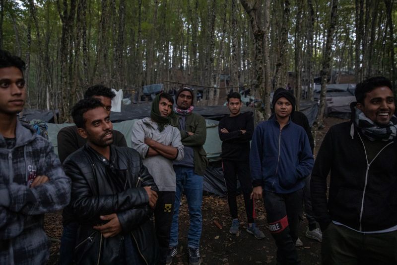 Migrants from Bangladesh stand in the woods near Velika Kladusa