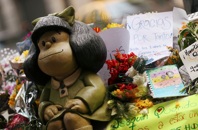 Flowers and tributes are seen next to a sculpture of