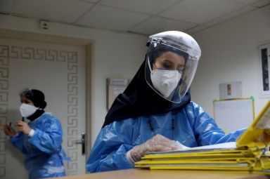 A nurse wearing a protective suit and mask checks the