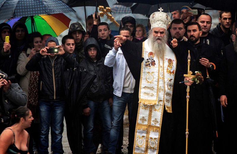 FILE PHOTO: Metropolitan Amfilohije Radovic throws a wooden cross in