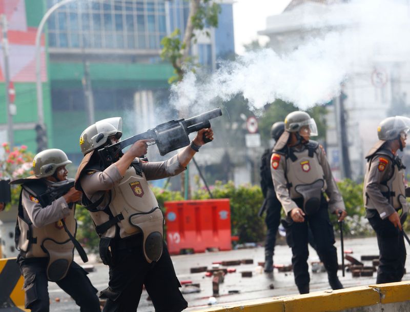 A riot police officer fires tear gas following a protest