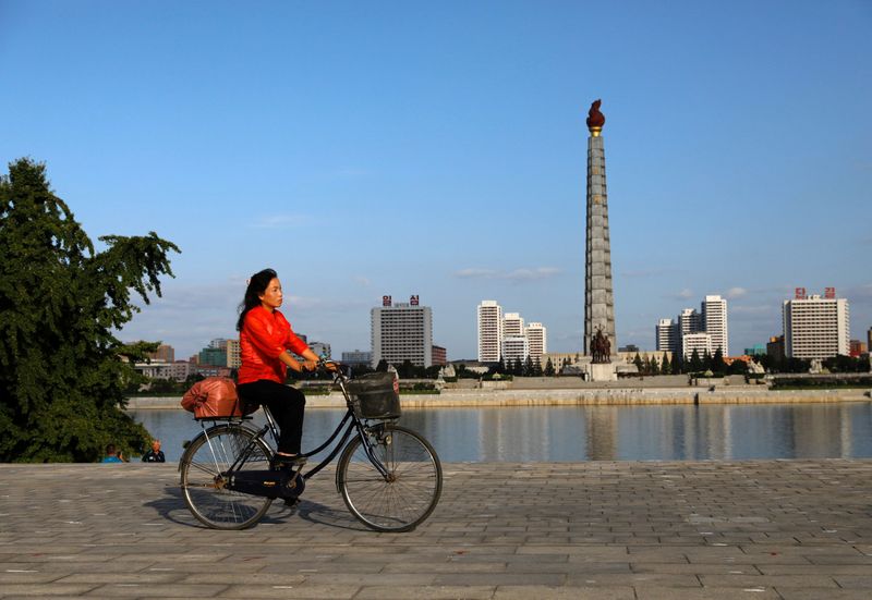 FILE PHOTO: A woman rides a bicycle as Juche Tower
