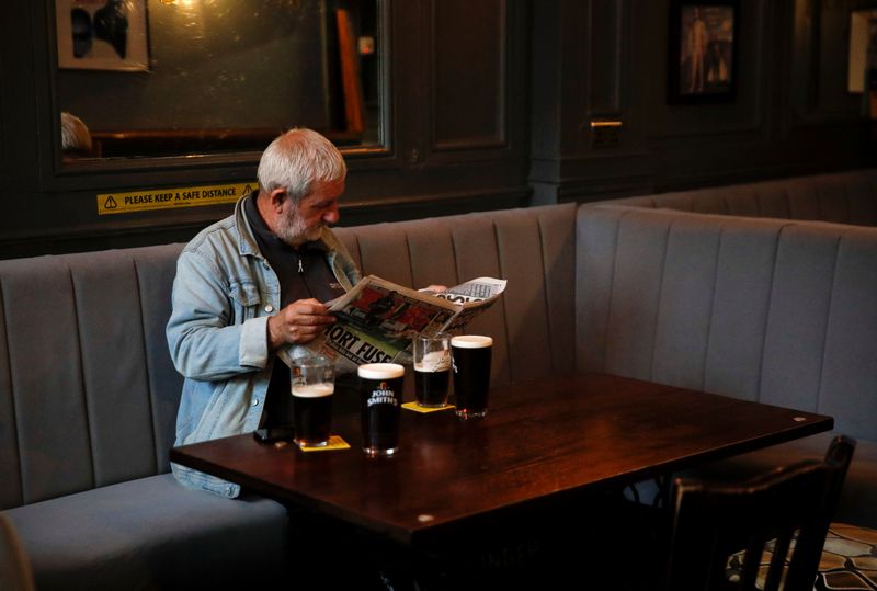 A man reads a newspaper as he sits inside the