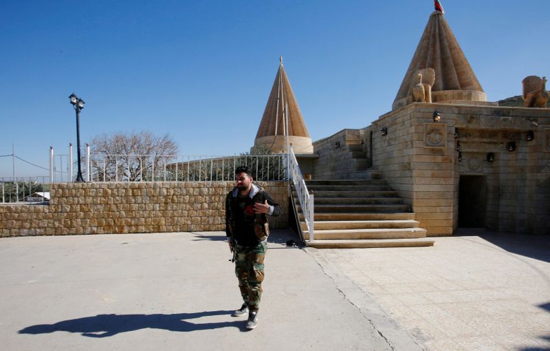 FILE PHOTO: A Yazidi fighter walks near Yazidi temple Sharaf