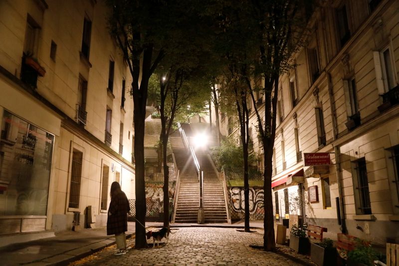 A woman walks her dog in Montmartre during the late-night