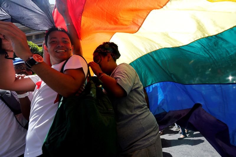 FILE PHOTO: Revellers smile as they hold a giant rainbow