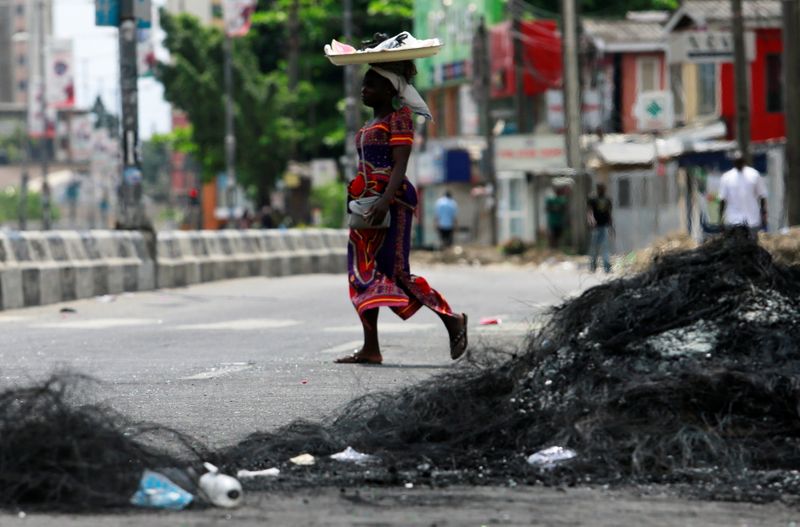A woman walks past the remains of a burnt barricade