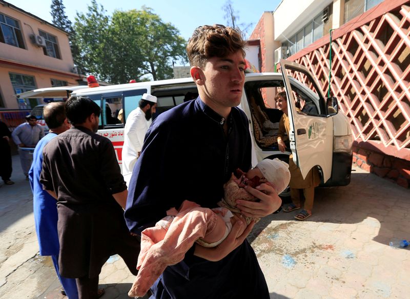 FILE PHOTO: A man carries an injured child at a