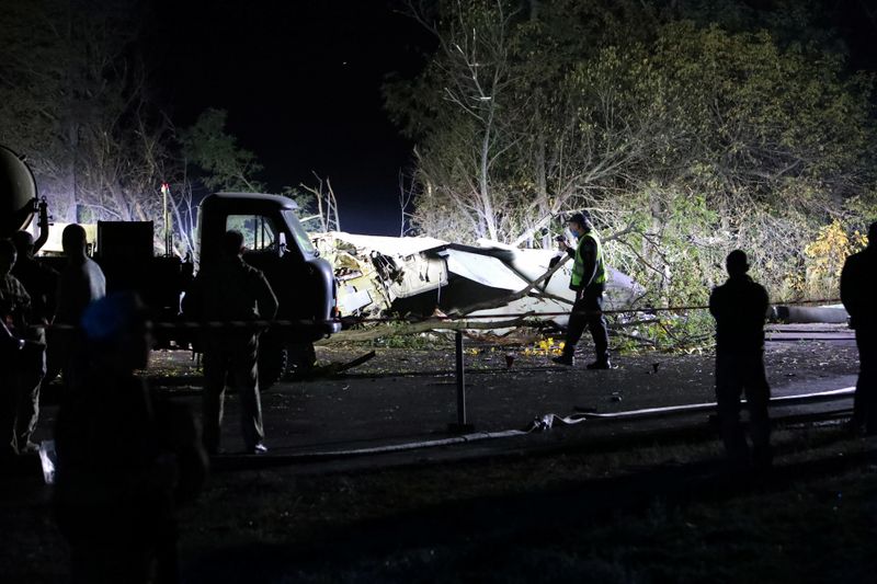 Rescuers inspect wreckages of the Ukrainian military Antonov An-26 plane