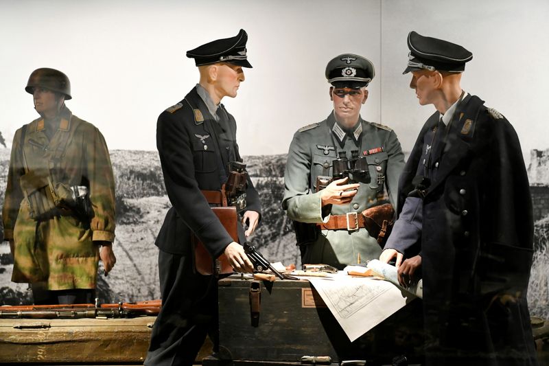 German uniforms, helmets and weapons are displayed behind armored glass