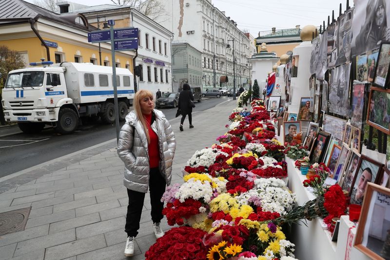 A woman stands next to a makeshift memorial outside the