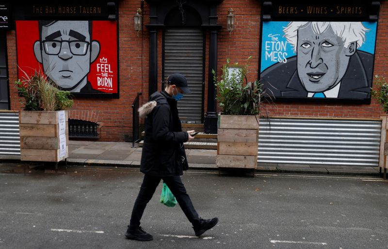 A woman walks past caricatures of Britain’s Prime Minister Boris