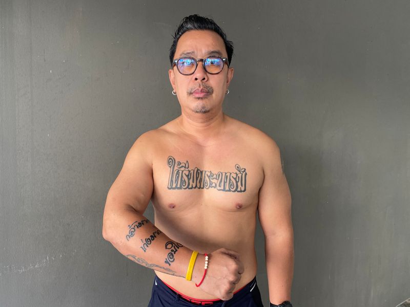 Royalist Thitiwat Tanagaroon shows his tattoos during an interview with