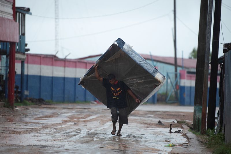 A man carries a mattress while moving to a shelter