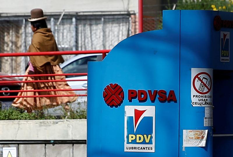 A woman walks next to a closed PDVSA fuel station