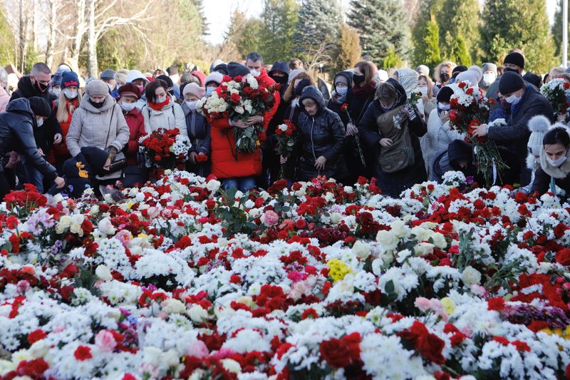 People lay flowers during a funeral of anti-government protester Roman