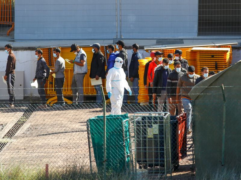 Migrants are seen in a military camp, where they are