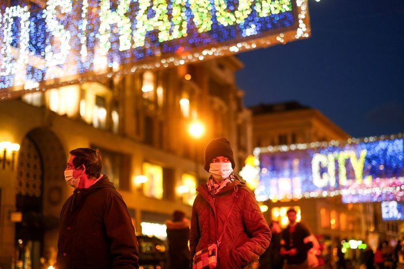 Pedestrians illuminated by Christmas lights walk through Oxford Street amid
