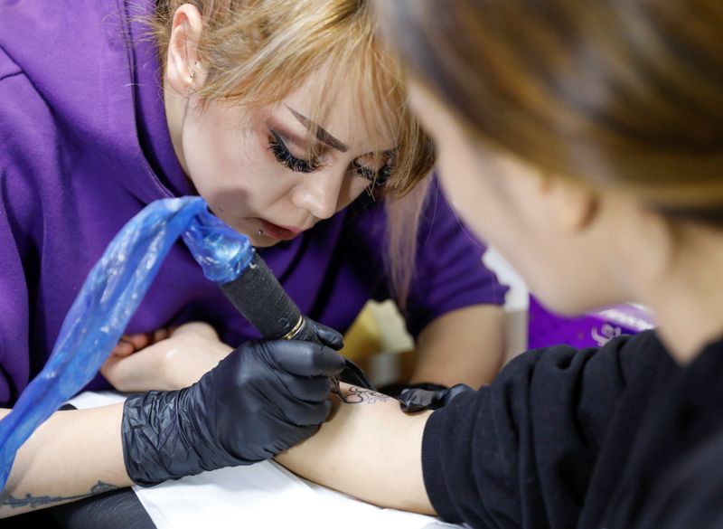Tattoo artist Soraya Shahidy, tattoos a client at her beauty
