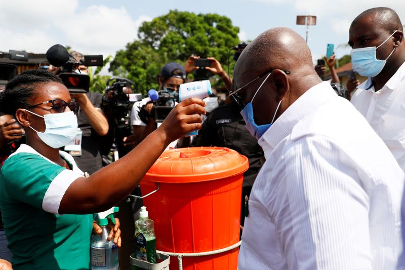 Staff member checks the temperature of Ghana’s President Nana Akufo-Addo