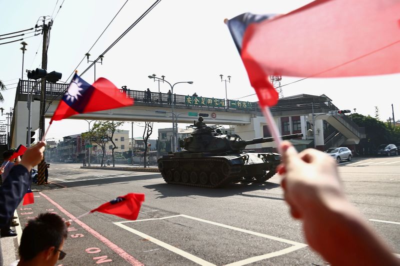 FILE PHOTO: People wave Taiwan’s flags while soldiers driving M60
