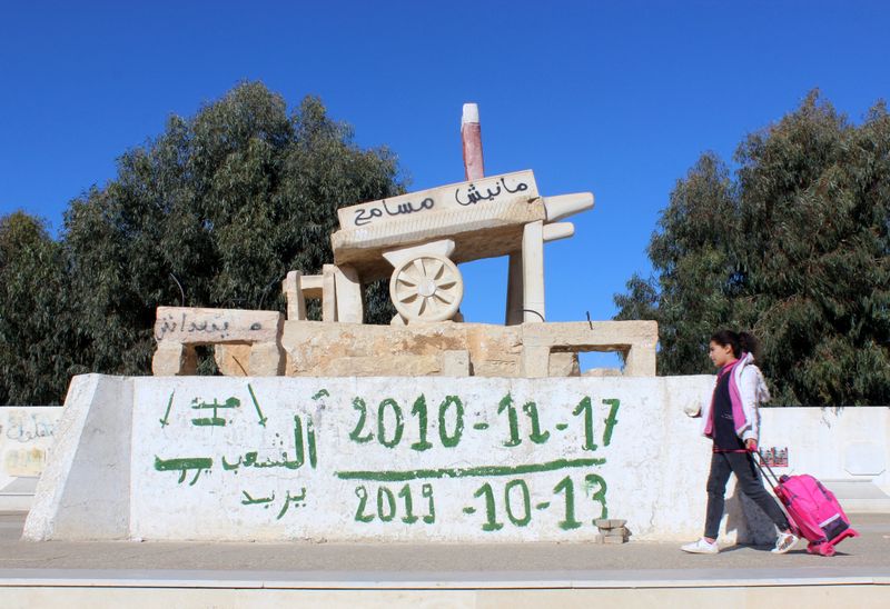 Girl walks past a memorial for Bouaziz in Sidi Bouzid