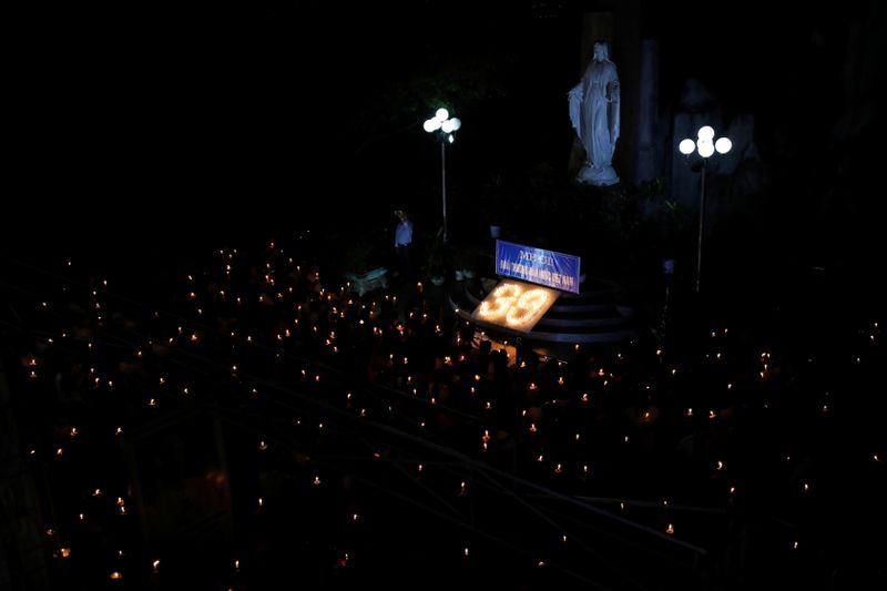 FILE PHOTO: Catholic believers hold lit candles during a mass