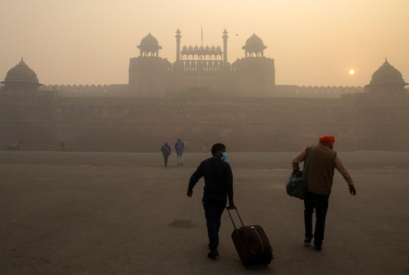 People arrive to visit the Red Fort on a smoggy
